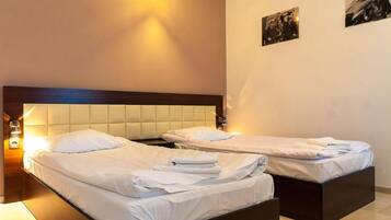 A hotel room with two beds, a wooden headboard, and a wall-mounted light fixture.