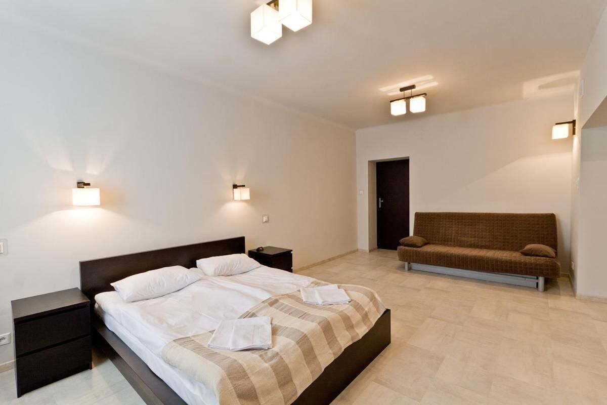 Une chambre moderne avec un grand lit, des tables de chevet, un canapé et des luminaires fixés au mur.