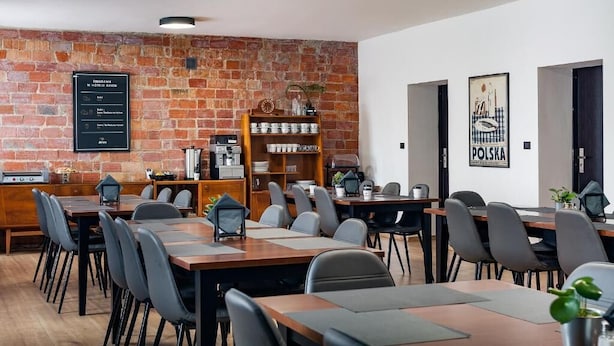 A modern meeting room with brick walls, wooden tables, and chairs.