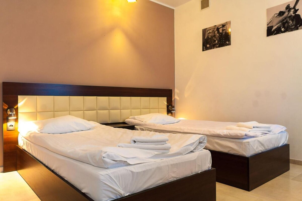 Een hotelkamer met twee bedden, een houten hoofdbord en een wandlamp.