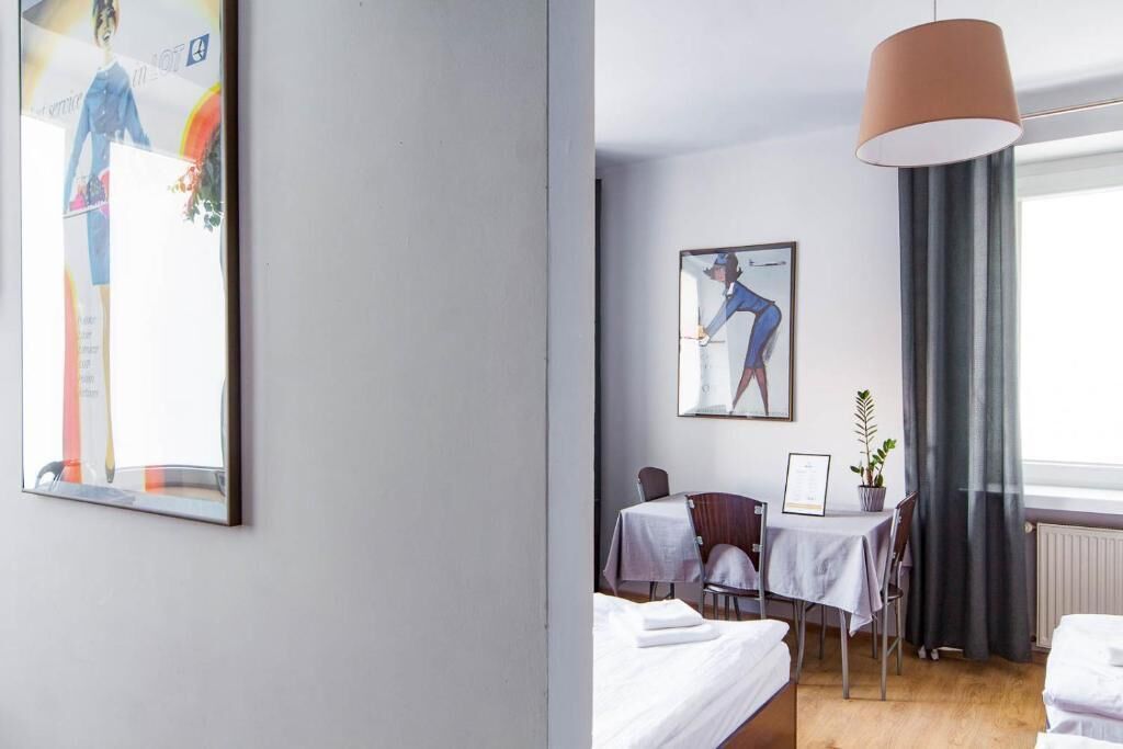Hotelkamer met een bed, bureau, stoel, tafel, hanglamp en kunstwerken aan de muren.