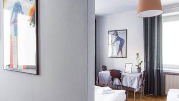 Hotelkamer met een bed, bureau, stoel, tafel, hanglamp en kunstwerken aan de muren.