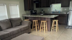 A modern kitchen with dark cabinets, a granite countertop, and a bar stool area.