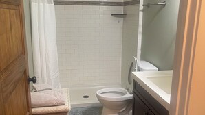 A bathroom with a shower, toilet, and sink.