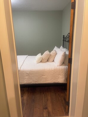 Une chambre à coucher avec un lit, des oreillers, une tête de lit en bois et un plancher en bois.