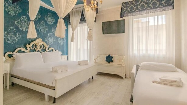 A bedroom with a large bed, a smaller bed, a sofa, a TV, and a chandelier. - Suites Train Station Mestre (Mestre)