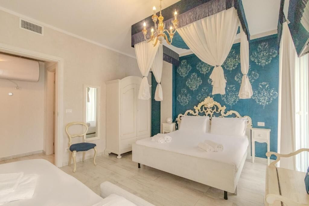 Un dormitorio con una cama grande, una araña, un armario y una silla.