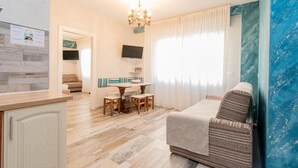 A living room with a sofa, a dining table, and a chandelier. - Suites Train Station Mestre (Mestre)
