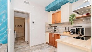 A compact kitchen with wooden cabinets, a coffee machine, and a microwave. - Suites Train Station Mestre (Mestre)