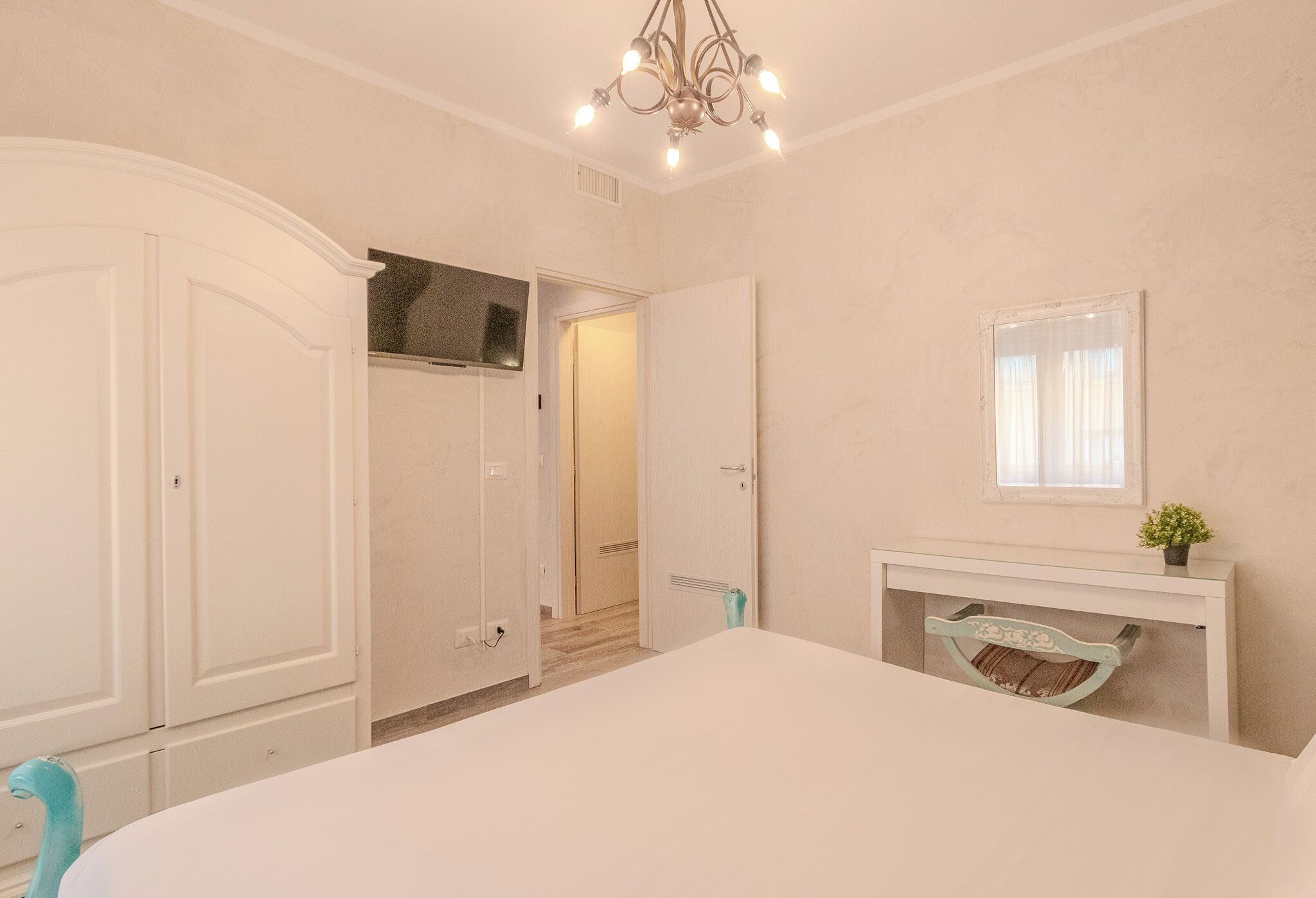 Un dormitorio con cama, armario, espejo, chimenea y puerta que da a otra habitación.