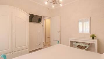 Un dormitorio con cama, armario, espejo, chimenea y puerta que da a otra habitación.