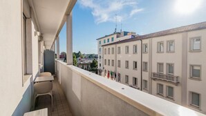 A balcony with a view of adjacent buildings, a railing, and a table with chairs. - Suites Train Station Mestre (Mestre)