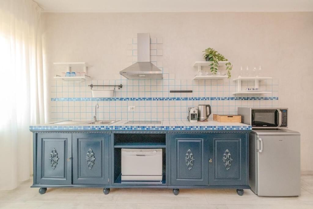 Una cocina con un armario azul, electrodomésticos blancos y un salpicadero de azulejos.