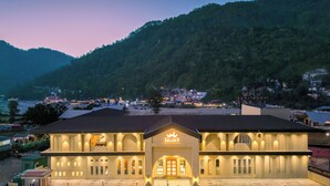 A hotel with a central courtyard, multiple floors, and a mountainous backdrop.