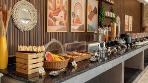 A buffet counter with various food items, a mirror, and framed artwork on the wall.