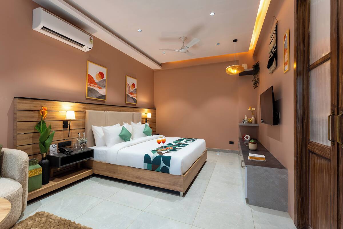 A modern hotel room with a wooden bed, a flat-screen TV, a desk, and a ceiling fan.