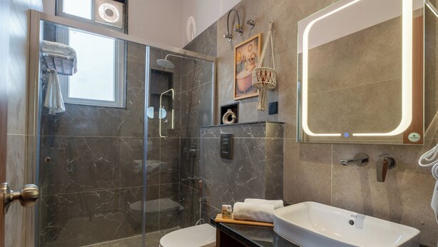 Ein modernes Badezimmer mit einer Duschkabine, einem großen Spiegel und einem weißen Waschbecken.