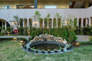 A courtyard with a circular water feature, potted plants, and a stone wall. - Moustache Select Rishikesh Mohanchatti (Sinduri)