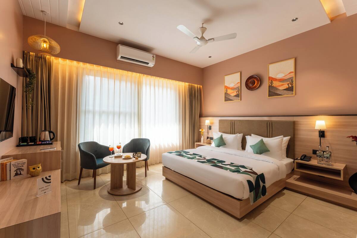 A hotel room with a bed, a desk, a chair, a round table, and a ceiling fan.