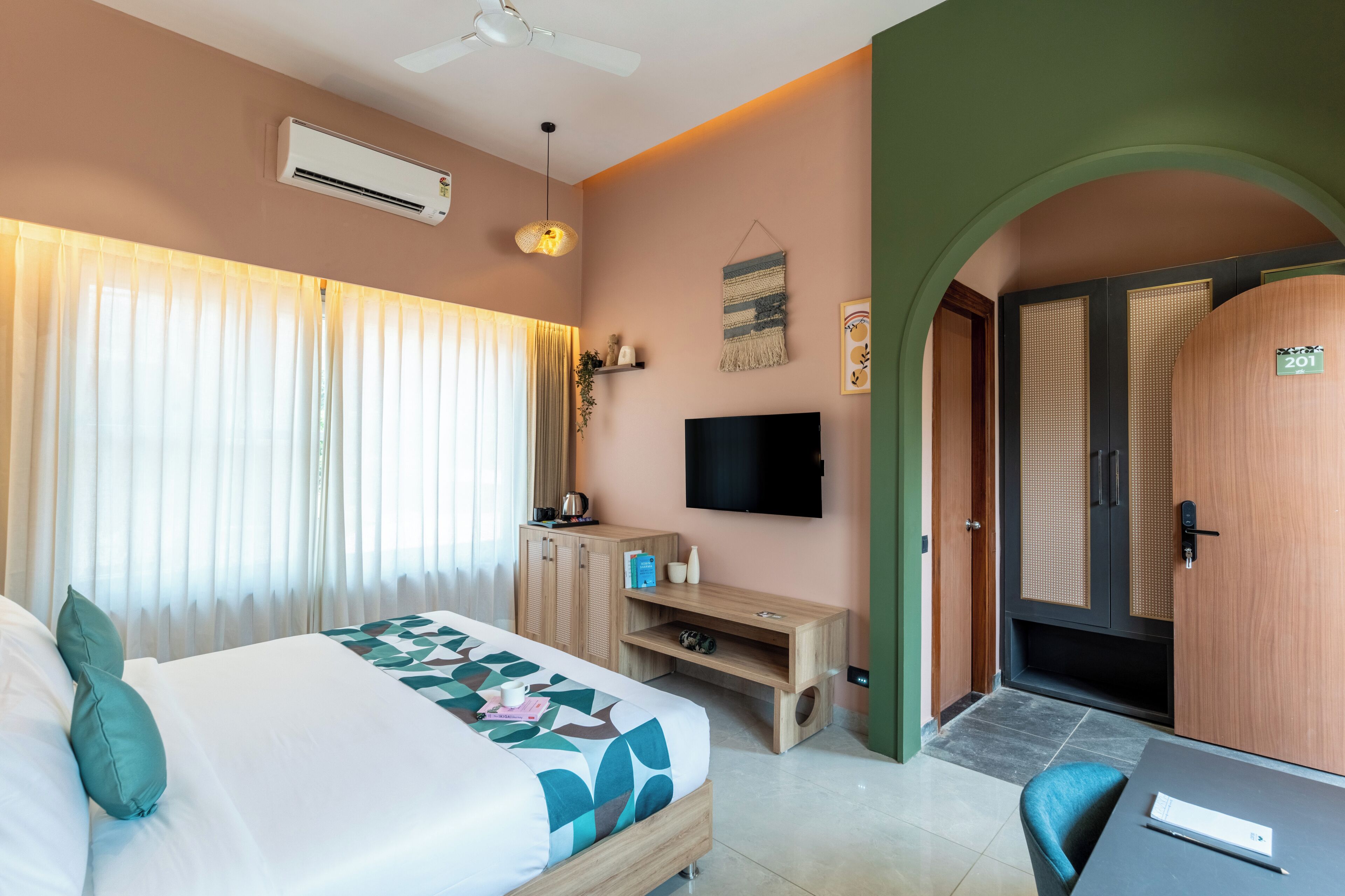 Une chambre d’hôtel avec un lit, une télévision, un bureau et une porte.