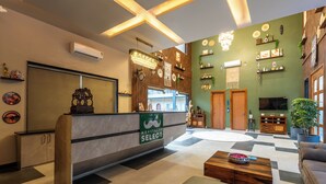 A reception area with a counter, a chandelier, a television, and a seating area with a coffee table.