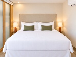 A hotel room with a large bed, two bedside lamps, and a wall-mounted air conditioner. - Unique house with direct access to the beach, four bedrooms, balcony and design (Ciudad de Panamá)