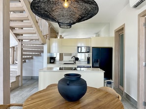 Une cuisine moderne dotée d’un îlot central, d’un luminaire suspendu et d’un escalier menant à un niveau supérieur.