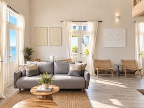 A modern living room with a grey sofa, two armchairs, a coffee table, and a view of the sea through large windows. - Unique house with direct access to the beach, four bedrooms, balcony and design (Ciudad de Panamá)