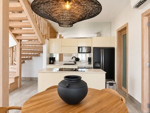 A modern kitchen with a central island, wooden staircase, and a hanging light fixture. - Unique house with direct access to the beach, four bedrooms, balcony and design (Ciudad de Panamá)