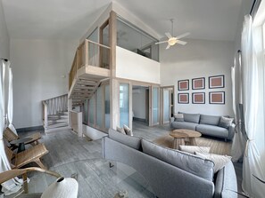 A modern living room with a staircase, a ceiling fan, a sofa, a coffee table, and framed artwork on the wall. - Unique house with direct access to the beach, four bedrooms, balcony and design (Ciudad de Panamá)