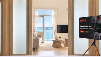 Une chambre d’hôtel avec un balcon, un lit, un téléviseur posé sur un meuble et une vue sur la mer.