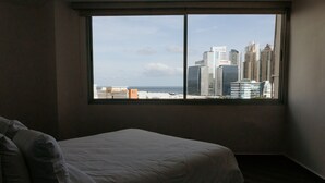 A bedroom with a large window, a bed, and a view of a city skyline. - Modern with terrace 2BR in Panama City 10B (Ciudad de Panamá)