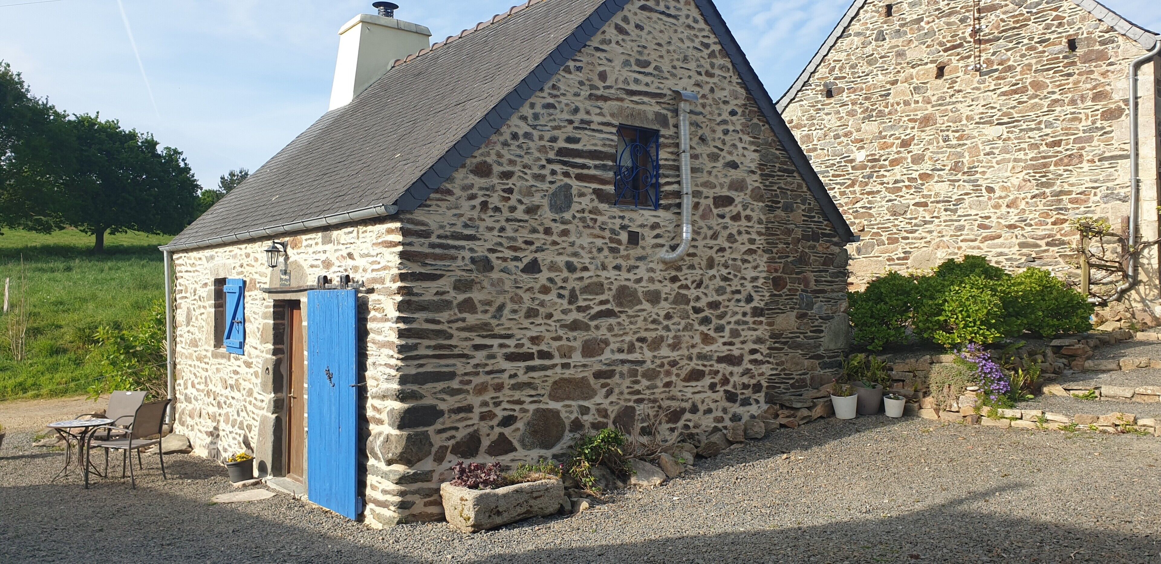 A stone building with a sloped roof, a blue door, and a small window.