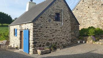 A stone building with a sloped roof, a blue door, and a small window.