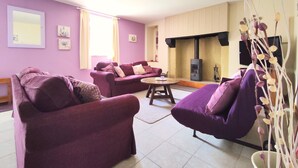 A living room with purple furniture, a fireplace, and a television. - Gîte Lavande - Pen Ar Voas Gîtes with Private Terrace, Shared Garden, and Wi-Fi (Plestin-les-Grèves)
