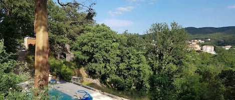 A swimming pool surrounded by lush greenery and a hillside view.