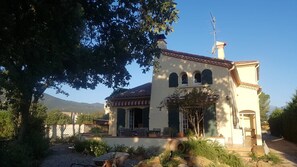 Un edificio a due piani con patio, posti a sedere all'aperto e vista sulle montagne.