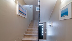 Eine Treppe führt zu einer Tür, an den Wänden befinden sich Bilder in Rahmen.