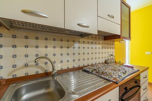 A kitchen with a stainless steel sink, white cabinets, and a yellow wall. - Apartment 'Plutone with Sea View Terrace', Wi-Fi and Air Conditioning (Portopalo di Capo Passero)