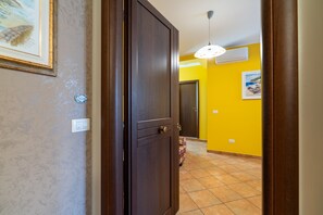 A hallway with a closed door, a light fixture, and a wall with a picture. - ‘Saturno’ Apartment Steps from the Sea with Balcony, Wi-Fi & Air Conditioning (Portopalo di Capo Passero)