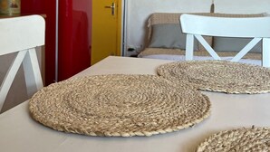 A room with a red refrigerator, a yellow door, a white table, and woven placemats. - 5-minute walk from the town center, magnificent view of the sea and the old town (Sète)