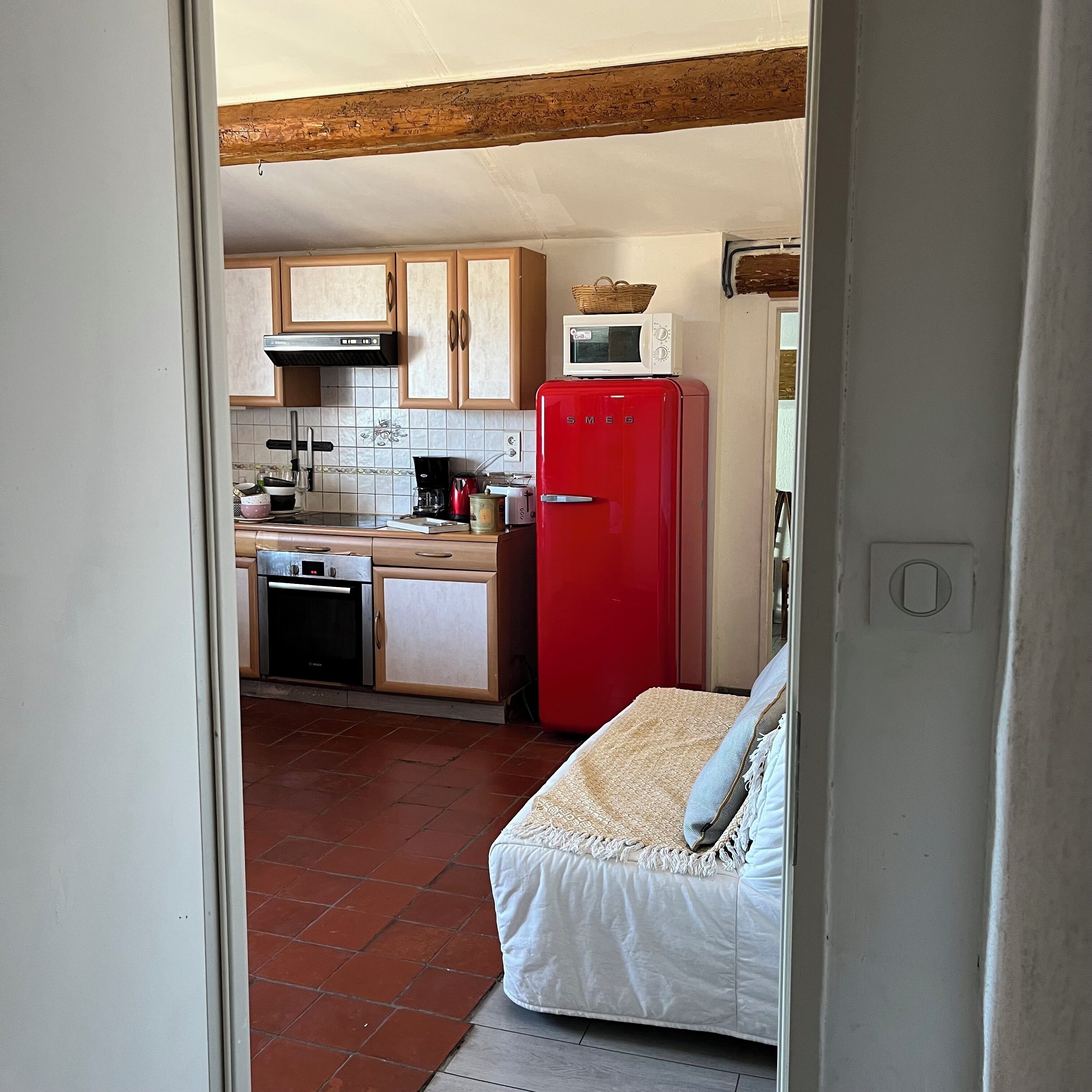 Une cuisine de taille réduite, avec un réfrigérateur rouge, un four à micro-ondes et une cuisinière.