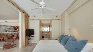 Un dormitorio con una cama grande, un televisor sobre un mueble bajo y vistas a la cocina.