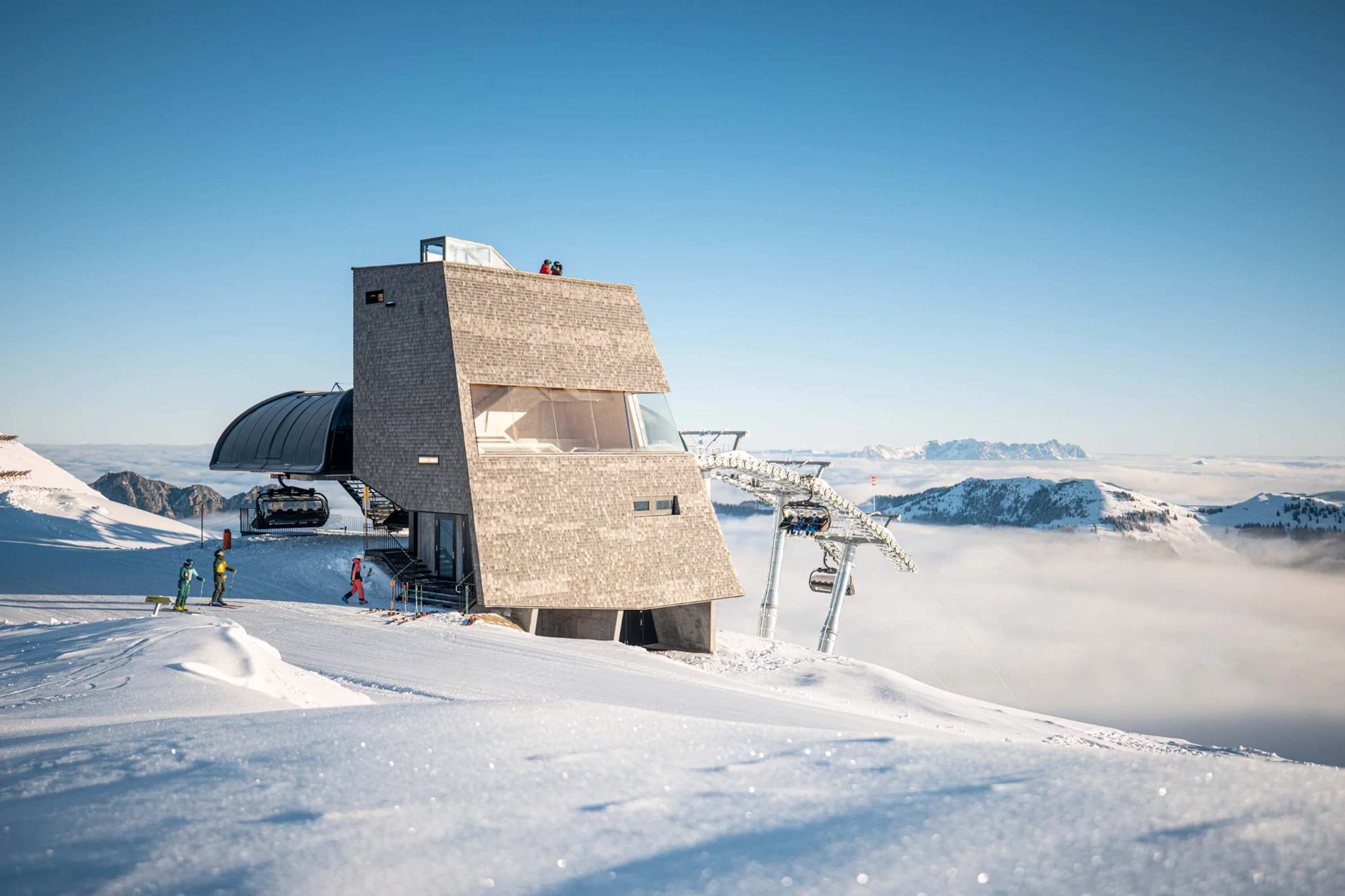 A snow-covered mountain with a ski lift and a building with a unique geometric design.