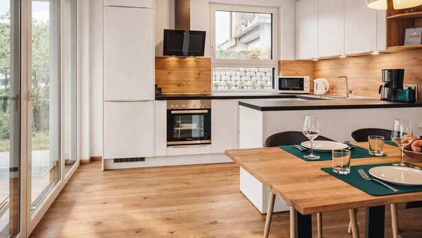 A modern kitchen with a built-in oven, microwave, and a large window. - ZWEITE HEIMAT – Cozy Apartment with Garden (Fügen)