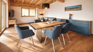A modern kitchen with a wooden table, blue chairs, and a blue cabinet. - ZILLERHEART – Apartment with Balcony & Mountain View (Fügen)