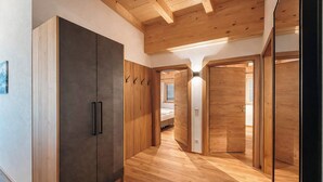 A hallway with wooden flooring, a wardrobe, and a bed in the background. - ZILLERHEART – Apartment with Balcony & Mountain View (Fügen)