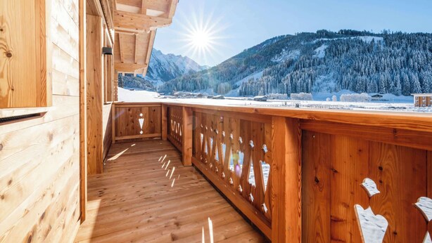 A wooden balcony with a view of snow-covered mountains and a clear sky. - BEIM LOIS Dorfblick – 2 Floors & Sauna Access (Gerlos)