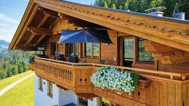A wooden chalet with a balcony, large windows, and a scenic mountain view. - HOCHEBEN – Balcony & Private Sauna (Ramsau im Zillertal)