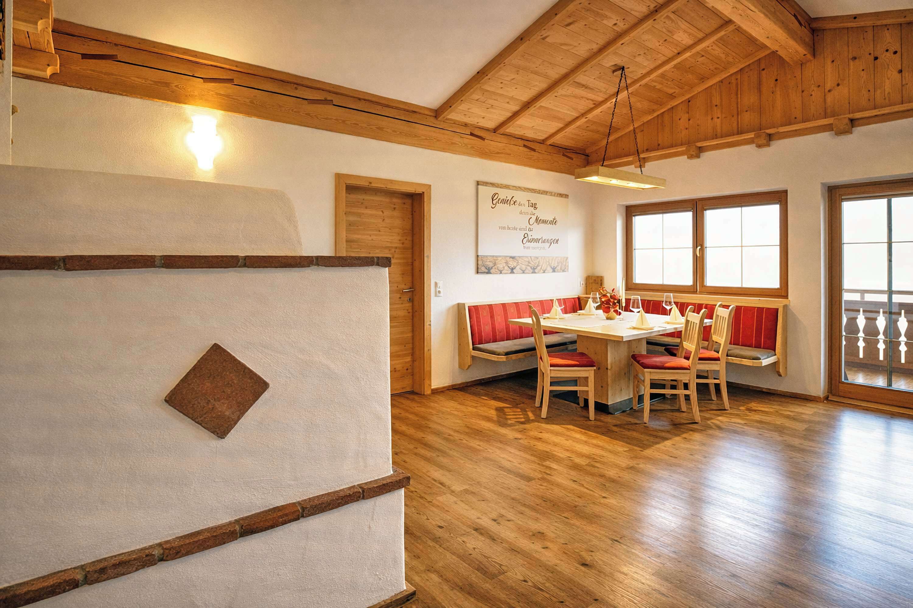Un comedor con una mesa y sillas de madera, un banco y una ventana con vistas.